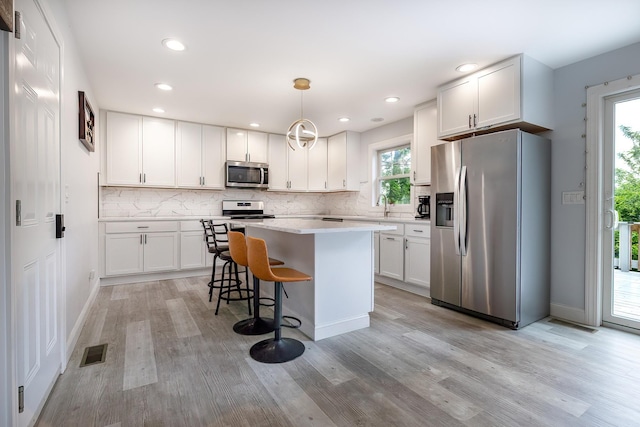 5 Teramar Way, White Plains, NY 10607 - kitchen with appliances with stainless steel finishes, light wood-style flooring, light countertops, a center island, and white cabinets