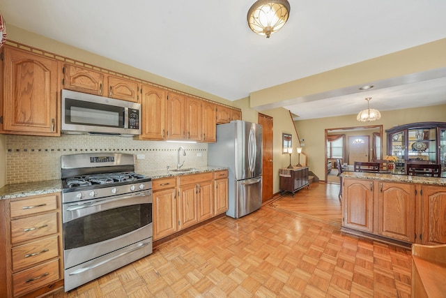 79-48 67th Rd, Middle Village, NY 11379 - kitchen featuring appliances with stainless steel finishes, a sink, decorative backsplash, pendant lighting, and light stone counters