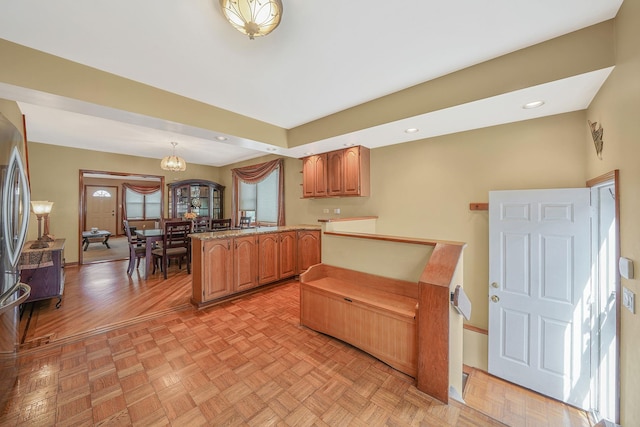 79-48 67th Rd, Middle Village, NY 11379 - kitchen featuring a peninsula, pendant lighting, brown cabinets, freestanding refrigerator, and a chandelier