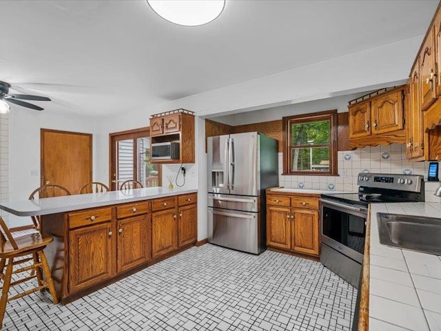708 Kirbytown Rd, Middletown, NY 10940 - kitchen with appliances with stainless steel finishes, tile countertops, a peninsula, and brown cabinets