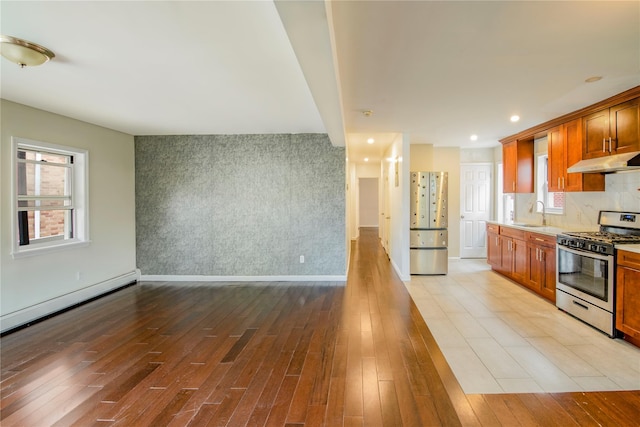 19623 56th Ave, Fresh Meadows, NY 11365 - kitchen with stainless steel gas stove, freestanding refrigerator, under cabinet range hood, light countertops, and plenty of natural light
