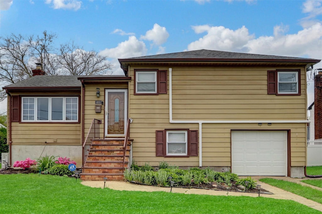 405 Miller Ave, Freeport, NY 11520 - tri-level home with an attached garage, a chimney, a front lawn, and entry steps