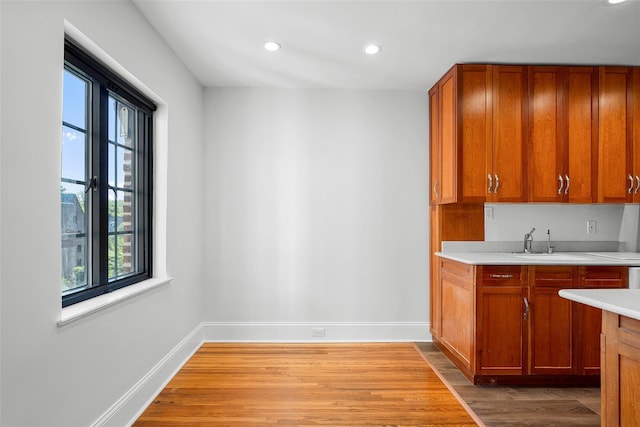 66 Milton Rd Unit C42, Rye, NY 10580 - kitchen with a sink, light countertops, light wood-type flooring, brown cabinetry, and recessed lighting