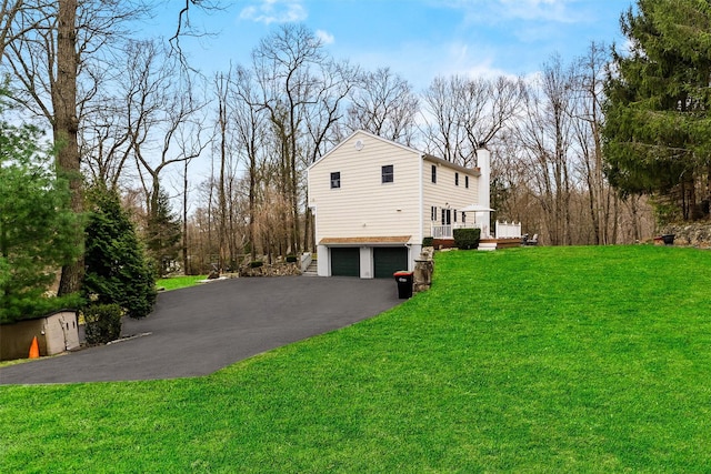 123 E St, South Salem, NY 10590 - view of side of home with a chimney, an attached garage, asphalt driveway, a wooden deck, and a yard