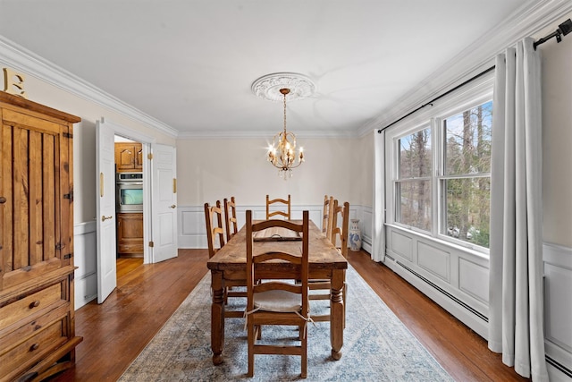 123 E St, South Salem, NY 10590 - dining area featuring ornamental molding, a chandelier, dark wood-style flooring, a wainscoted wall, and a baseboard heating unit