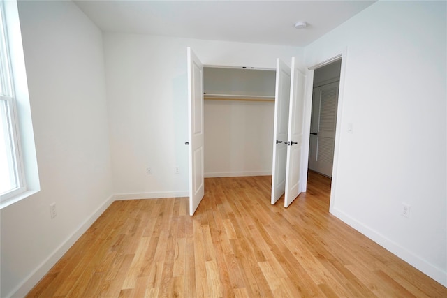 unfurnished bedroom with light wood-style floors, a closet, and baseboards