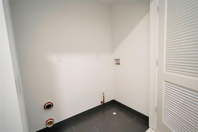 clothes washing area with gas dryer hookup, washer hookup, dark tile patterned flooring, and baseboards