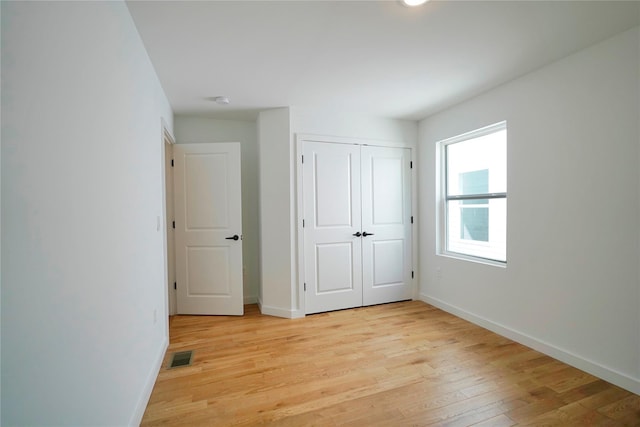 unfurnished bedroom featuring light wood-style flooring, baseboards, and a closet