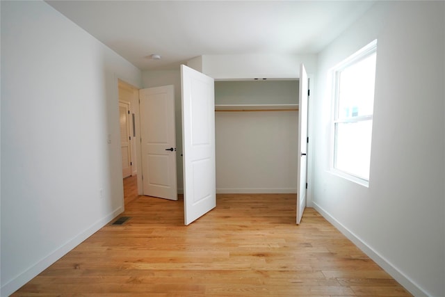 unfurnished bedroom with light wood-type flooring, baseboards, and a closet