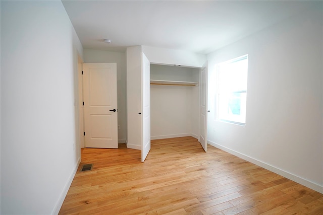 unfurnished bedroom with light wood-style flooring, baseboards, and a closet