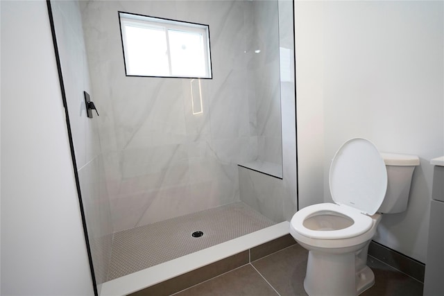 bathroom featuring toilet, a tile shower, and tile patterned flooring