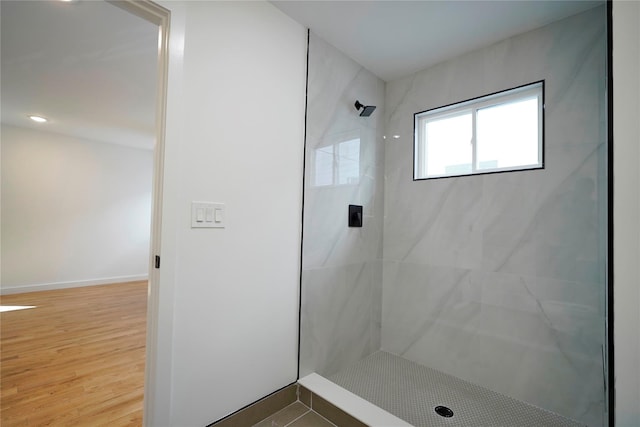 bathroom featuring tiled shower, wood finished floors, and baseboards