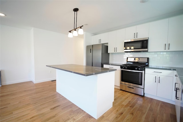 kitchen with appliances with stainless steel finishes, light wood finished floors, tasteful backsplash, and dark countertops