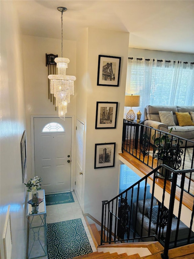entryway with a chandelier, tile patterned flooring, and baseboards