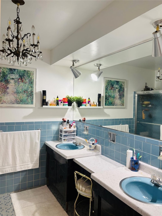 full bath with tile walls, vanity, a chandelier, a stall shower, and a wainscoted wall