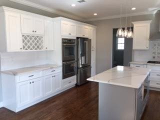 110B Louis St, Massapequa, NY 11758 - kitchen featuring stainless steel double oven, freestanding refrigerator, white cabinets, dark wood-style flooring, and a kitchen island