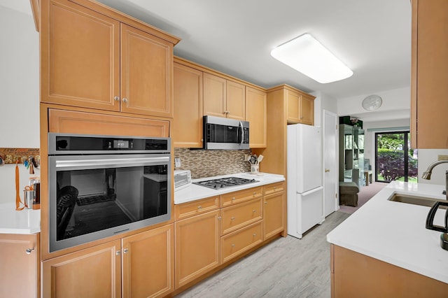 48 Old Lake Rd, Congers, NY 10920 - kitchen featuring appliances with stainless steel finishes, a sink, light wood-type flooring, decorative backsplash, and light countertops