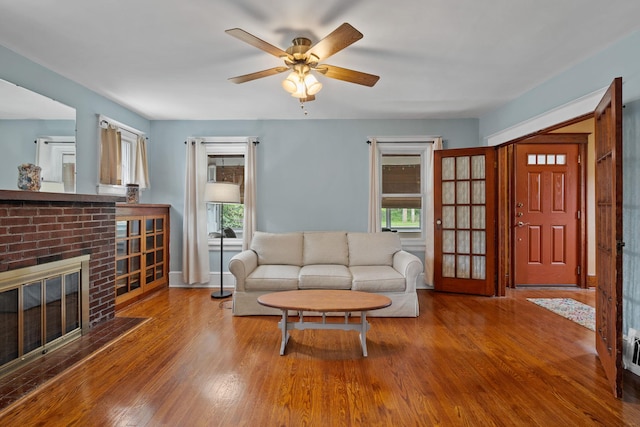 323 Hooker Ave, Poughkeepsie, NY 12603 - living area featuring wood finished floors, a brick fireplace, a ceiling fan, and plenty of natural light