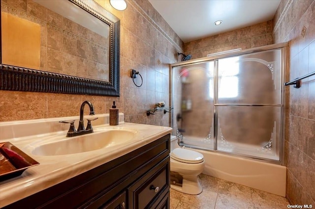 252-14 82nd Rd, Bellerose, NY 11426 - bathroom featuring tile walls, vanity, toilet, and bath / shower combo with glass door