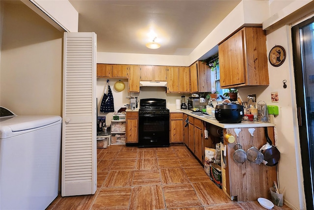 120-16 Cove Ct Unit 87A, College Point, NY 11356 - kitchen featuring black gas range oven, washer / clothes dryer, under cabinet range hood, brown cabinetry, and light countertops