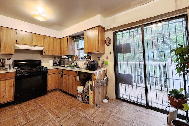 120-16 Cove Ct Unit 87A, College Point, NY 11356 - kitchen with black gas range, under cabinet range hood, light countertops, and brown cabinetry