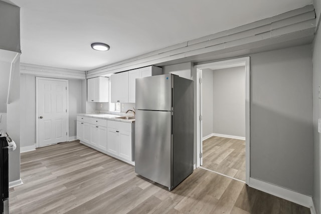 7 Grant St, Poughkeepsie, NY 12601 - kitchen featuring freestanding refrigerator, a sink, white cabinets, light wood-type flooring, and light countertops