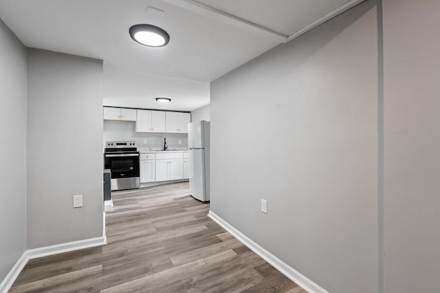 7 Grant St, Poughkeepsie, NY 12601 - kitchen featuring stainless steel electric range, freestanding refrigerator, baseboards, and white cabinets