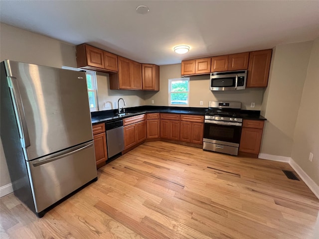 692 Burlingham Rd, Bloomingburg, NY 12721 - kitchen with appliances with stainless steel finishes, light wood finished floors, dark countertops, brown cabinets, and baseboards