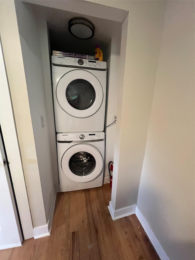 692 Burlingham Rd, Bloomingburg, NY 12721 - clothes washing area featuring stacked washer and clothes dryer, wood finished floors, and baseboards
