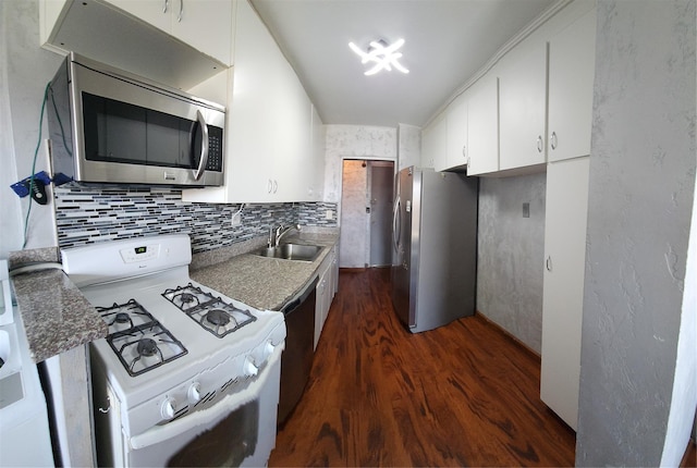 kitchen featuring appliances with stainless steel finishes, a sink, dark wood-type flooring, white cabinetry, and tasteful backsplash