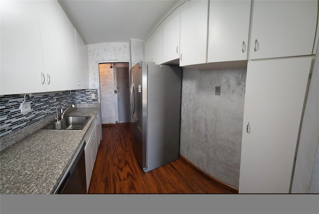 kitchen with appliances with stainless steel finishes, dark wood-style floors, a sink, white cabinetry, and tasteful backsplash
