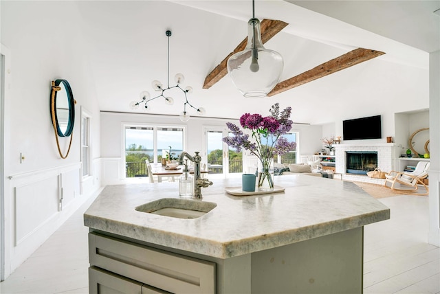 6 Beech Hollow Ct, Montauk, NY 11954 - kitchen with a sink, beam ceiling, a kitchen island with sink, light stone counters, and a fireplace