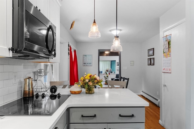 3 Sebastian Ct, Hopewell Junction, NY 12533 - kitchen featuring black appliances, a baseboard heating unit, tasteful backsplash, a peninsula, and wood finished floors