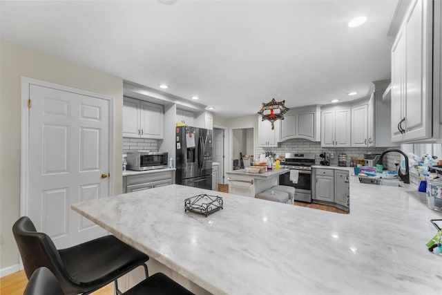 150 Cedar Ave, Poughkeepsie, NY 12603 - kitchen with appliances with stainless steel finishes, a sink, backsplash, a peninsula, and a breakfast bar area