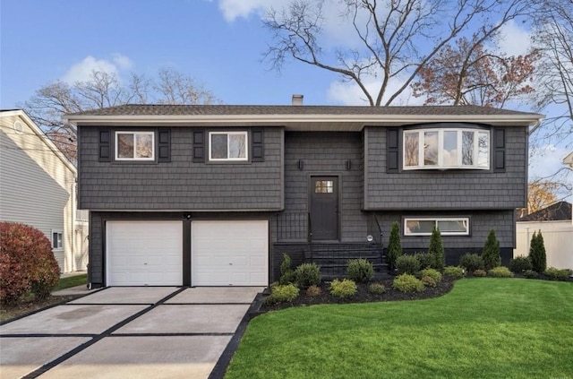 split foyer home with a front yard, concrete driveway, an attached garage, and a chimney