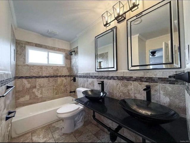bathroom with ornamental molding, a sink, tile walls, tub / shower combination, and toilet