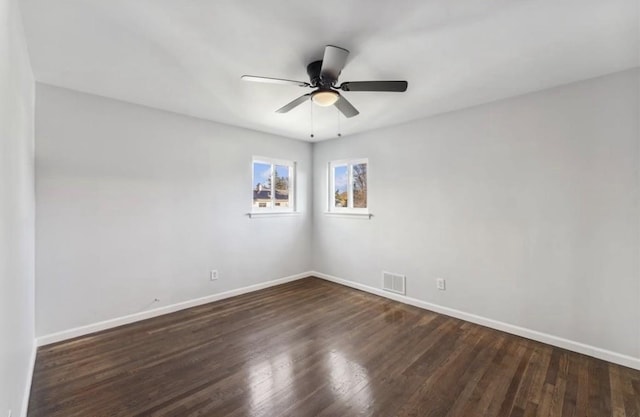 spare room with baseboards, dark wood-style floors, and ceiling fan