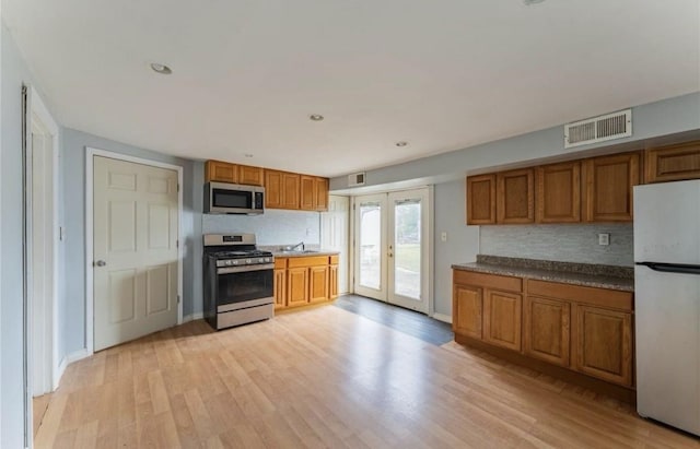 kitchen with stainless steel appliances, brown cabinets, french doors, decorative backsplash, and recessed lighting