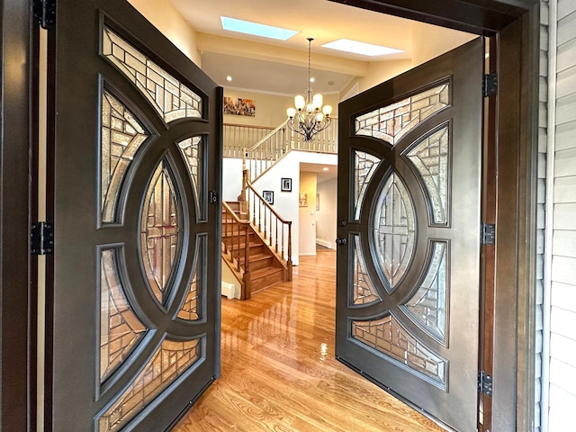 9 Hill And Tree Ct, Melville, NY 11747 - entryway featuring a chandelier, light wood-type flooring, stairway, a skylight, and a towering ceiling