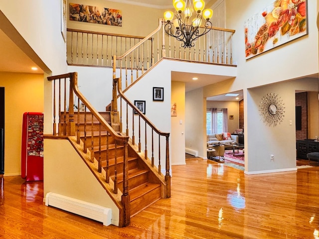 9 Hill And Tree Ct, Melville, NY 11747 - stairs featuring a baseboard radiator, wood finished floors, a high ceiling, a chandelier, and baseboards