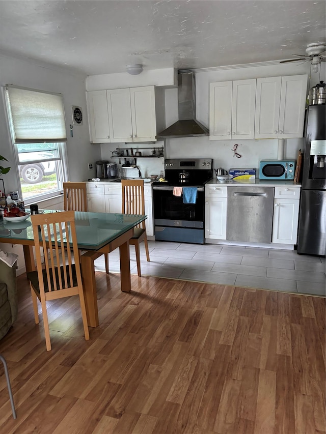 109 Convent Rd, Syosset, NY 11791 - kitchen with stainless steel appliances, wall chimney range hood, light wood-style floors, and white cabinets