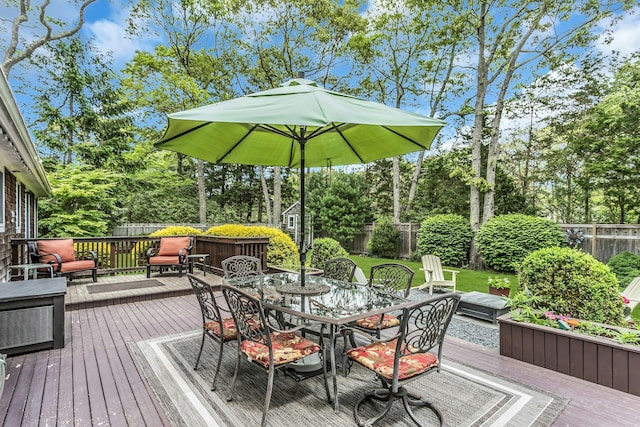 deck featuring outdoor dining area and view of wooded area