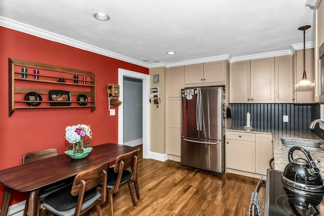 kitchen featuring freestanding refrigerator, a sink, crown molding, dark wood-style flooring, and light stone counters