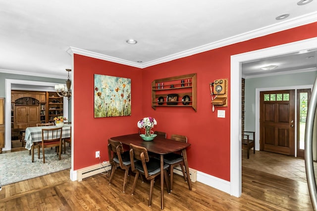dining space with a baseboard heating unit, baseboards, a chandelier, wood finished floors, and crown molding