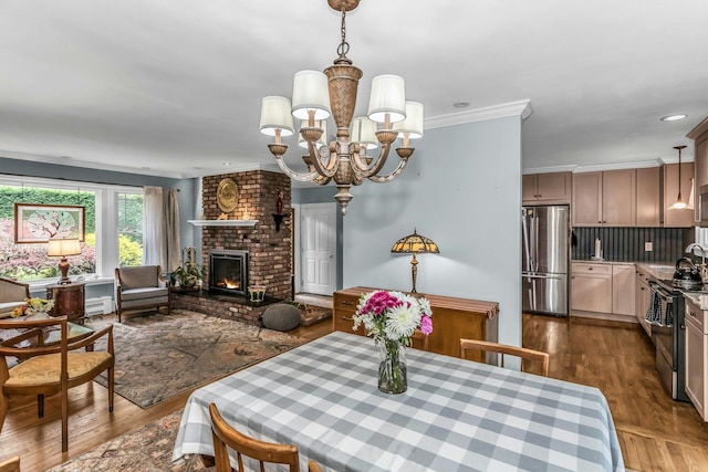 dining area featuring a chandelier, a brick fireplace, dark wood-style flooring, and ornamental molding