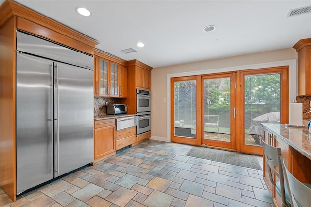 525 Green Pl, Woodmere, NY 11598 - kitchen with stainless steel appliances, backsplash, a warming drawer, glass insert cabinets, and light stone countertops