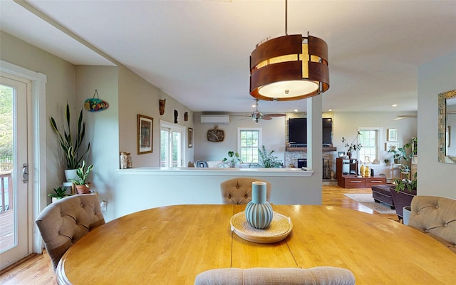 395 Toleman Rd, Washingtonville, NY 12575 - dining room with wood finished floors, a ceiling fan, an AC wall unit, and a fireplace