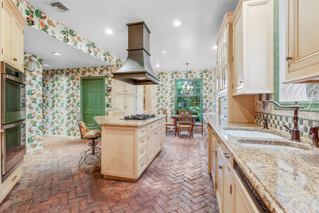 66 Susan Dr, Newburgh, NY 12550 - kitchen featuring wallpapered walls, island exhaust hood, cream cabinetry, brick floors, and gas stovetop
