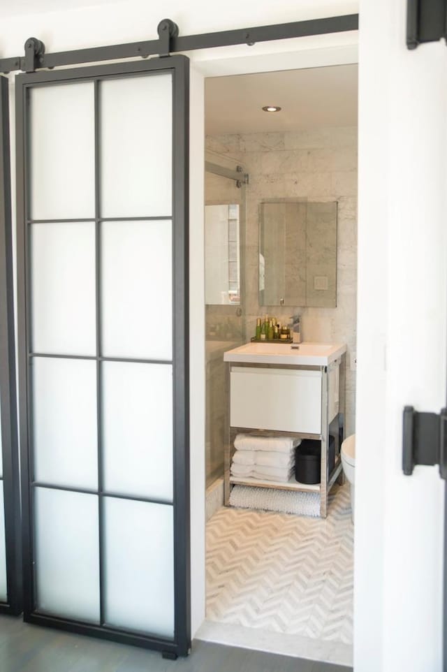 bathroom with toilet, tile walls, vanity, and a shower