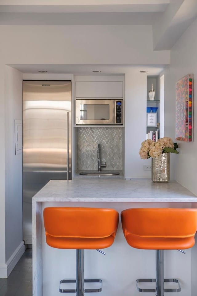indoor bar with built in appliances, backsplash, and wood finished floors